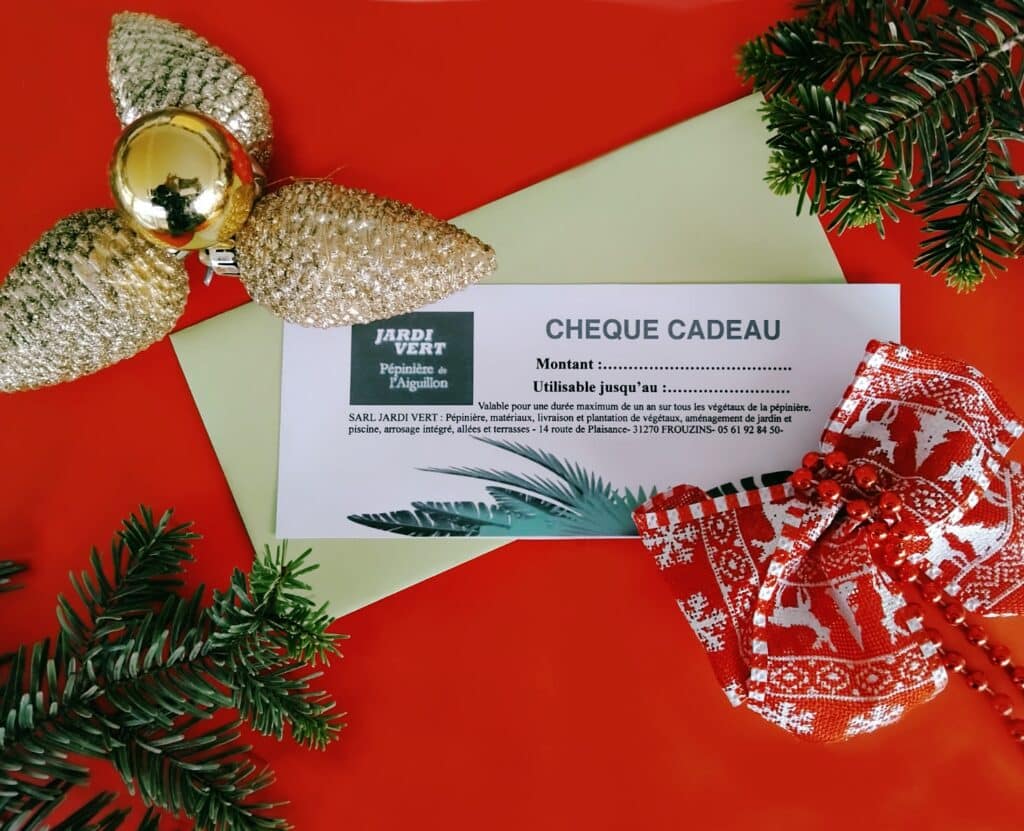 Chèque cadeau de Jardi Vert Pépinière de l'Aiguillon sur fond rouge vif avec décorations de Noël dorées et branche de sapin.
